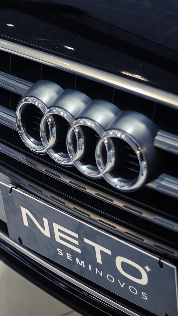 Frente de um Audi no salão da Neto Seminovos, com a placa da loja